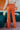 Back view of the Missed Decade Flare Pants that features an orange colored corduroy material, a high-rise waist, a button and zipper front closure, faux front pockets, two back pockets, and a flare fit.