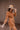 Side view of model wearing the More Than Enough Romper In Camel, which has a camel corduroy material, a collar neck, a surplice front, a long sleeve with a button, a front zipper, pockets, and pleating on the legs.