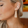 The Fall Feelings Earring is a dangle style earring, featuring a gold half circle stud, an ivory colored body, and an orange and yellow print.