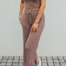 Front view of model wearing The Work It Out Tie Pant which features soft mocha-colored ribbed fabric, an elastic drawstring waist, and wide legs with side slits.