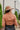 Back view of model wearing the Walk Away Top, which features a copper colored material, a collar neck, a surplice neckline, long sleeves, and a front tie closure.