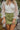 Close-up front view of model wearing the Loved You First Corduroy Skort that has green corduroy with a front zipper closure, belt loops, front pockets, faux back pockets, and a front skirt overlay.