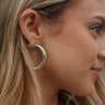 Close side view of model wearing the Isabella Silver Hoop Earrings, which feature open silver hoops.