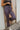 Close front view of model wearing the On To The Next Pants, which feature stretchy textured fabric with a black, blue, purple, and cream geometric print, a high-rise elastic waist, and straight legs.