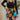 Close front view of model wearing the Feeling It Floral Skirt, which features black satin fabric with a multi-colored floral print, a black lining, a small side slit, and a side zipper