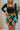 Close front view of model wearing the Feeling It Floral Skirt, which features black satin fabric with a multi-colored floral print, a black lining, a small side slit, and a side zipper