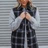 Front view of model wearing the Go Your Own Way Plaid Vest that has black and white plaid flannel fabric, tortoise buttons, a collared neckline, slits on each side of the hem, and a longline hem