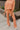 Front view of model wearing the Setting The Vibe Pants, that have an orange terry cloth ribbed material, an elastic waist band with a tie, two front pockets, and a straight leg fit. worn with matching top.