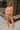 Full body front view of model wearing the Setting The Vibe Pants, that have an orange terry cloth ribbed material, an elastic waist band with a tie, two front pockets, and a straight leg fit. worn with matching top.