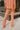 Back view of model wearing the Setting The Vibe Pants, that have an orange terry cloth ribbed material, an elastic waist band with a tie, two front pockets, and a straight leg fit. worn with matching top.