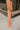 Side view of model wearing the Setting The Vibe Pants, that have an orange terry cloth ribbed material, an elastic waist band with a tie, two front pockets, and a straight leg fit. worn with matching top.