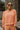 Front view of model wearing the Setting The Vibe Top, which has an orange terry cloth ribbed material, a round neck, long cuffed sleeves, a thick bottom hem, and side slits. Worn with matching pants