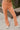 Close-up front view of model wearing the Setting The Vibe Pants, that have an orange terry cloth ribbed material, an elastic waist band with a tie, two front pockets, and a straight leg fit. worn with matching top.