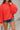 Frontal view of the Walk The Line Sweater that features a red knit material, a round neck, a long sleeve, a front pocket, a high-low design, and a flowy fit.