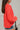 Side view of the Walk The Line Sweater that features a red knit material, a round neck, a long sleeve, a front pocket, a high-low design, and a flowy fit.