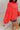Side view of the Walk The Line Sweater that features a red knit material, a round neck, a long sleeve, a front pocket, a high-low design, and a flowy fit.