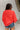 Back view of the Walk The Line Sweater that features a red knit material, a round neck, a long sleeve, a front pocket, a high-low design, and a flowy fit.