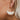 The Squared Away Earring is a dangle style earring, featuring an open gold arch, a gold half circle body, and a multi-colored beading at the edge.