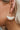 The Squared Away Earring is a dangle style earring, featuring an open gold arch, a gold half circle body, and a multi-colored beading at the edge.