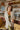 Frontal view of the happy Hour Blazer that features an ivory material, a collar and lapel, a two button front closure, a long sleeve, shoulder pads, two front pockets, and a back slit.