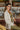Side view of the happy Hour Blazer that features an ivory material, a collar and lapel, a two button front closure, a long sleeve, shoulder pads, two front pockets, and a back slit.