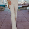 Frontal view of the Let's Chat Pants that features a beige colored material, a high-rise waist, a sweetheart cut waist hemline, a seam down the front legs, a wide leg fit, and a back zipper closure.