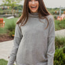 Frontal view of the Moment In Time Top that features a heather grey knit material, a high neckline, long cuffed sleeves, and a thick bottom hem.