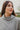 Frontal view of the Moment In Time Top features a heather grey knit material, a high neckline, long cuffed sleeves, and a thick bottom hem.