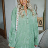 Front view of model wearing the Loved You First Dress that has light green fabric, a button-up front with a collared neckline, a high-low hem, and long sleeves with buttoned cuffs