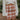Close up front view of The Toccoa River Plaid Skirt in Cognac features cognac and white knit fabric, plaid pattern, front slit on the left side, mini length and back zipper closure.