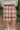 Back view of The Toccoa River Plaid Skirt in Cognac features cognac and white knit fabric, plaid pattern, front slit on the left side, mini length and back zipper closure.