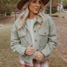 Front view of The Less Is More Shacket features light sage suede fabric, cropped waist, two front chest pockets with tortoise buttons, tortoise button up with a collared neckline, and long sleeves with buttoned cuffs.
