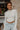 Frontal view of the See You Around Top that features a white material a high neckline, a long sleeve, lettuce edge hems, and a patchwork design.
