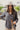 Frontal view of the Bare With Me Top that features a charcoal grey gauze material, a V neckline, a button-up front, a long cuffed sleeve, raw hemlines through out, and side pockets.
