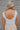 Back view of model wearing the Play It Cool Bodysuit that has white ribbed fabric, a v-neckline, a sleeveless body, a thong bottom and hook closures.