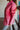 Side view of the Seasons Change Jacket that features a pink colored corduroy material, a collar and lapel neckline, a two button front closure, a long sleeve, two front pockets, and a back slit.