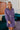 Frontal view of the Purple Haze Corduroy Dress that features a purple corduroy material, a long cuffed sleeve, a collar neck, a button-up front, two front pockets, an adjustable belt, and a mini length.