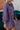 Side view of the Purple Haze Corduroy Dress that features a purple corduroy material, a long cuffed sleeve, a collar neck, a button-up front, two front pockets, an adjustable belt, and a mini length.