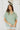 Front view of model wearing the Can't Go Wrong Top, which has a sage green colored material, a collar neck, a button-up front, a short cuffed sleeve, a front pocket, and a flowy fit
