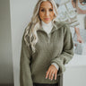 Front view of The Richmond Sweater features olive green cable knit fabric, quarter zip up with a high neckline and long balloon sleeves with cuffed wrists
