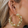 Side view of model wearing the Flower Fantasy Gold Earrings which features gold flowers covered hoops.