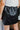 Back view of the Enough For Me Skirt that features a black colored PU material, a cross-over front design, a front panel with an adjustable tie, a back elastic band waist, and a mini length.