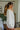 Side view of the Perfect Timing Top that features an ivory colored material, a collar neck, a 3/4 button-up, a long sleeve, two front pockets, and an oversized fit.