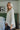 Side view of the Easy Breezy Top that features a cream colored knit material, an open knit design, a V neckline, a long cuffed sleeve, side slits, and a high-low design.