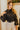 Front view of model wearing The Parisian Wonder Top features a black crochet material, a high round neckline, long sheer sleeves, lace detail at the neckline, a lining underneath, and a back zipper closure.