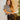 Frontal view of the Timeless Top that features a black colored material, a white houndstooth pattern, short sleeves, gold button detailing at the shoulder, and fringe detailing at the hems.