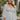 Frontal view of the Pocket Full Of Sunshine Top that features a white chiffon material, a black flower print, a sweetheart neckline, a long sleeve, a babydoll silhouette, and a smocked back.