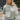 Frontal view of the In A Minute Sweater that features a moss green knit material, a white checkered design, a round neck, and long sleeves