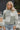 Frontal view of the In A Minute Sweater that features a moss green knit material, a white checkered design, a round neck, and long sleeves