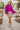 Full body front view of model wearing the Take Me Out Top, which features a purple colored material, a collar V neck with a button, a long flowy sleeve with a smocking at the wrist, a draped bottom hem. Tucked into beige skirt.